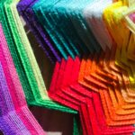 Detalle en primer plano de un mandala artesanal tejido con hilos de colores vibrantes.
