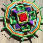 Mandala artesanal tejido en capas de colores intensos con terminaciones verdes.