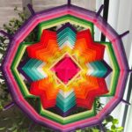 Diseño artesanal en tonos morado, verde y dorado.