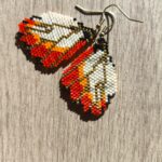 Pendientes tejidos a mano en forma de alas de mariposa con cuentas Miyuki en tonos naranja, blanco y dorado.